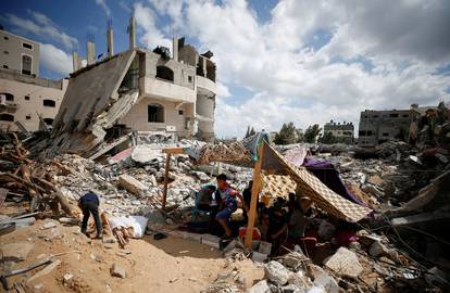 Palestinians sit in tents amid the rubble of their houses which were destroyed by Israeli air strikes