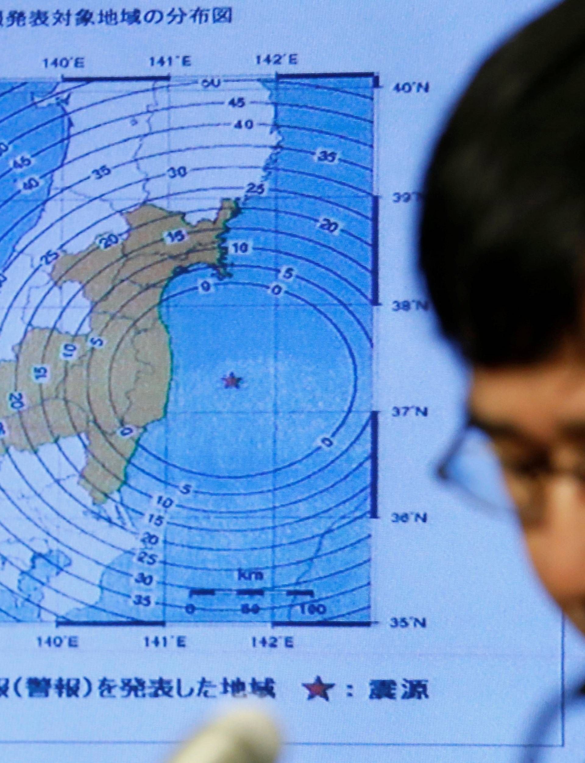 Japan Meteorological Agency's earthquake and volcano observations division director Koji Nakamura addresses a news conference next to the map showing an earthquake epicenter, in Tokyo