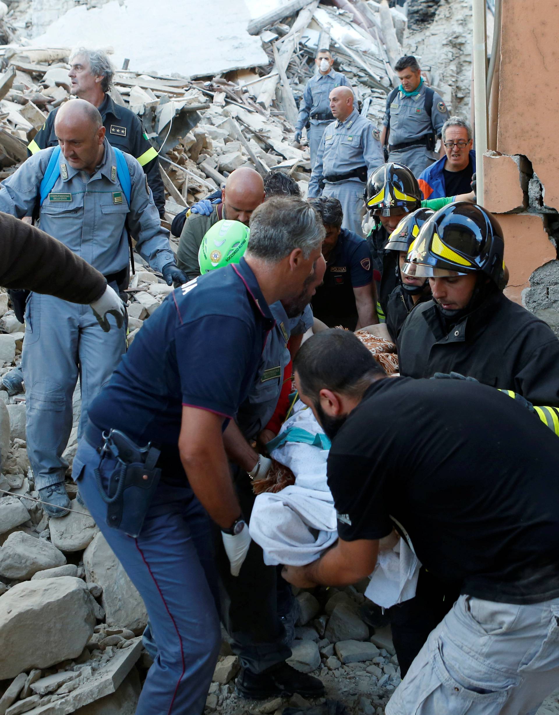 Rescuers carry a person on a stretcher following a quake in Amatrice 