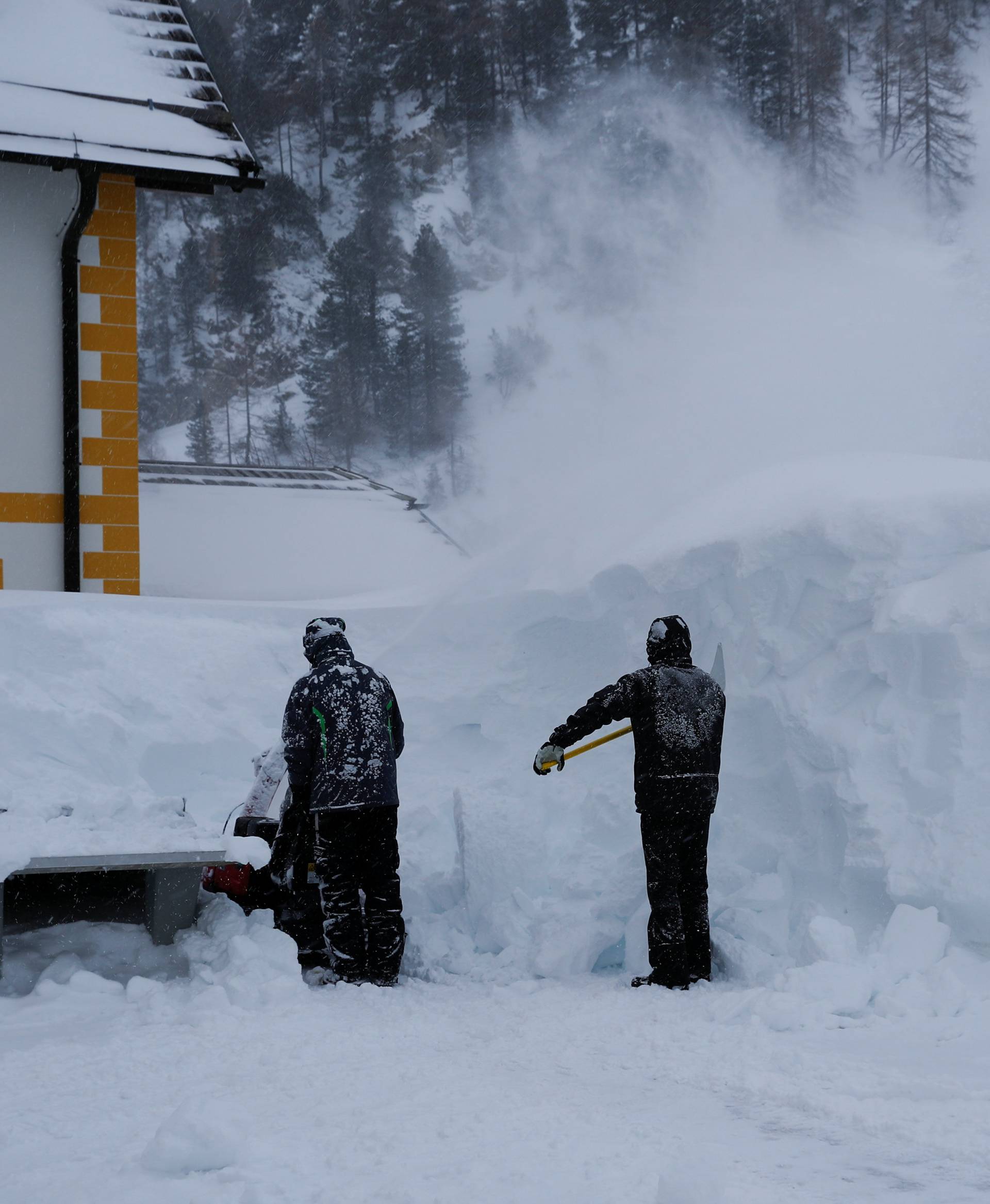 Two workers remove snow after heavy snowfall in Obertauern