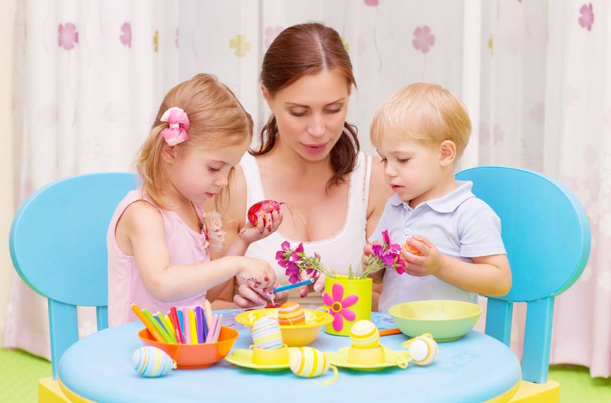 Mother with kids paint Easter eggs