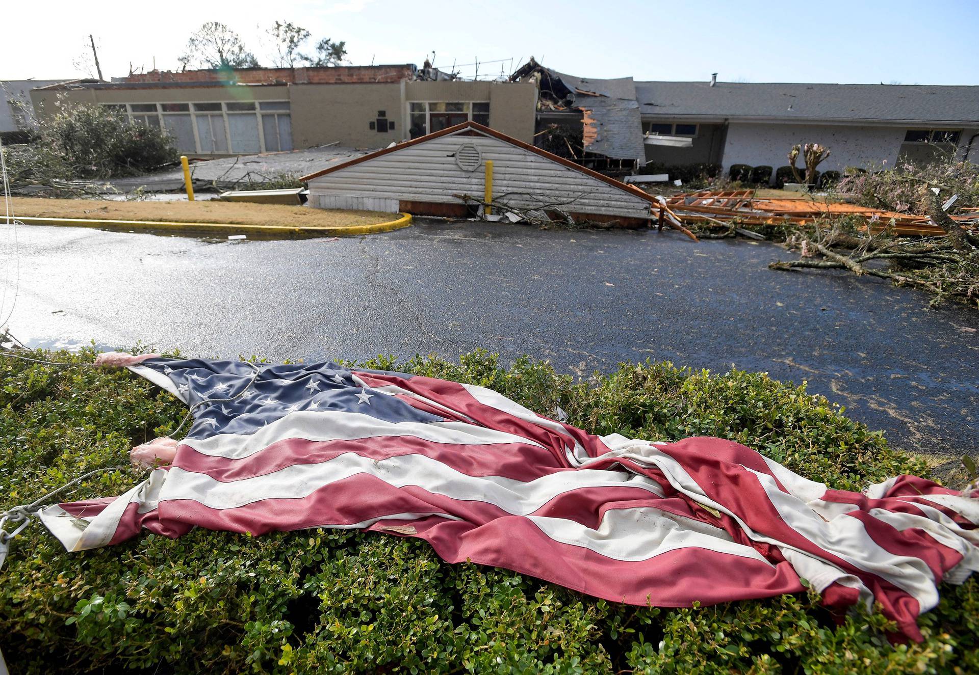 The American flag lies in the shrubs in front of the storm damaged Selma Country Club