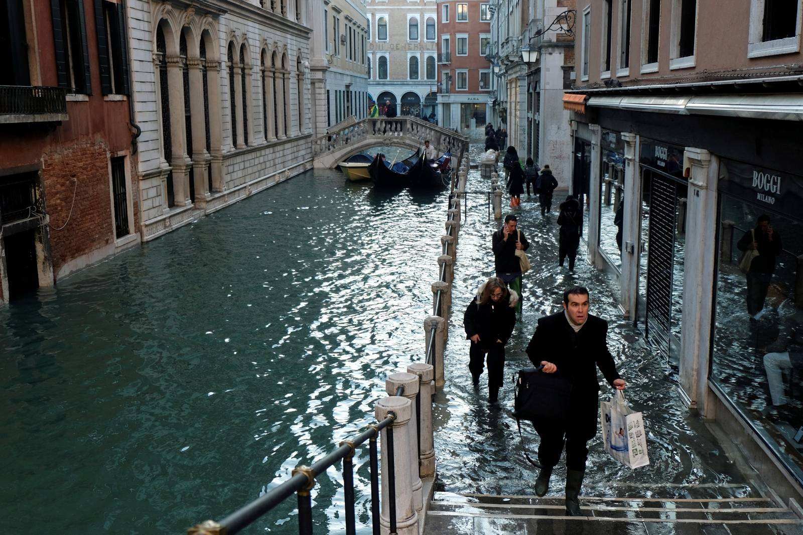 People walk on a flooded street during high tide in Venice