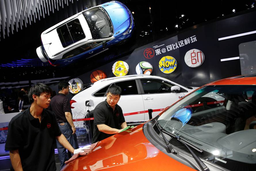 Members of staff clean a vehicle presented at BYD booth during Auto China 2016 auto show in Beijing