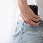 a woman's hand pulls out a mobile phone from the back pocket of her jeans. Close-up