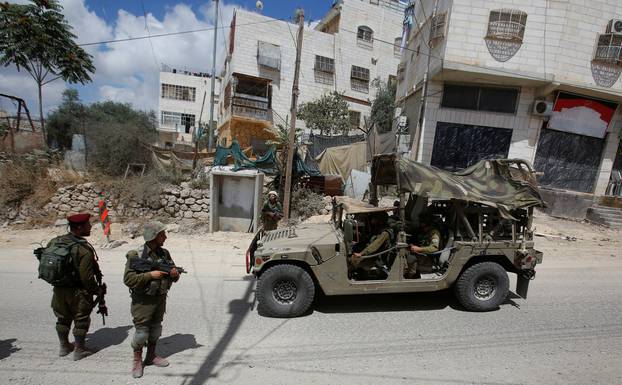 Israeli soldiers stand at the scene of attempted car ramming attack, in Hebron in the occupied West Bank city of Hebron