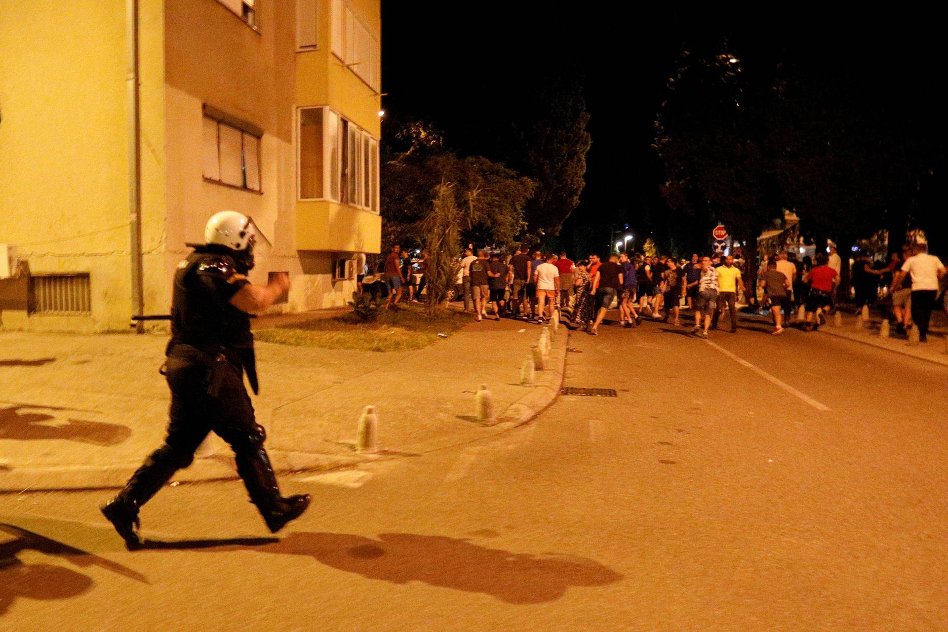 A member of riot police is seen near protestors in front of a police station in Podgorica