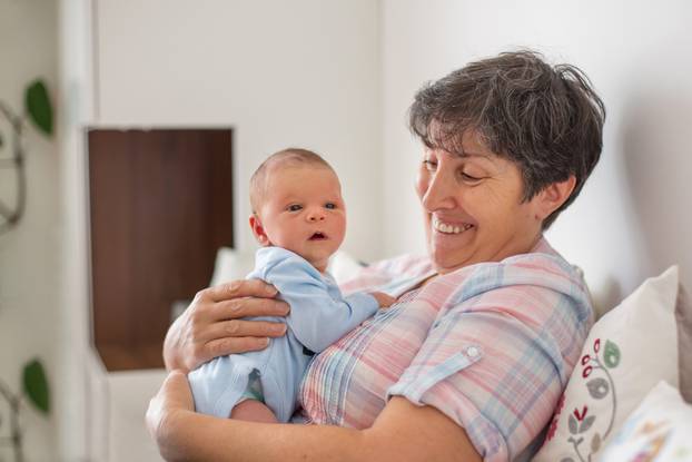 Beautiful baby boy in grandmothers arms