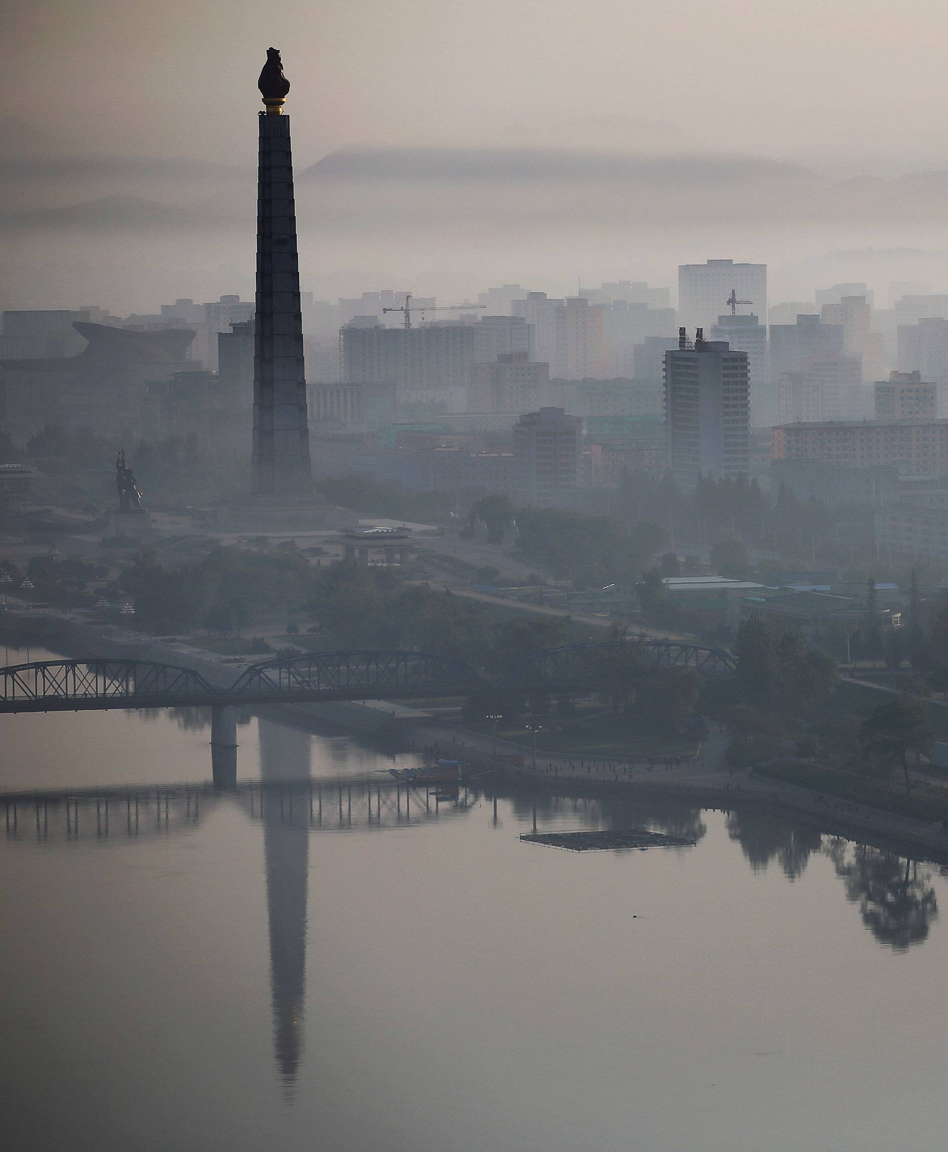 The 170-metre (558-feet) tall Juche Tower is reflected in Taedong River as morning fog blankets Pyongyang