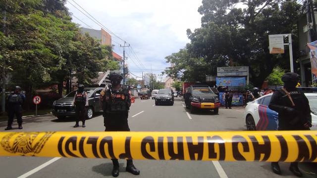 Armed police officers stand guard along a closed road following an explosion outside a Catholic church in Makassar, Indonesia