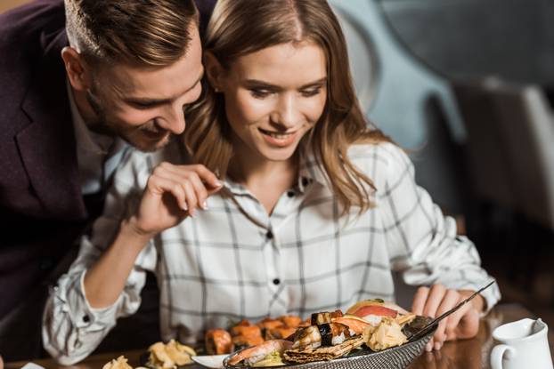 Attractive smiling young adult couple having dinner in restaurant 