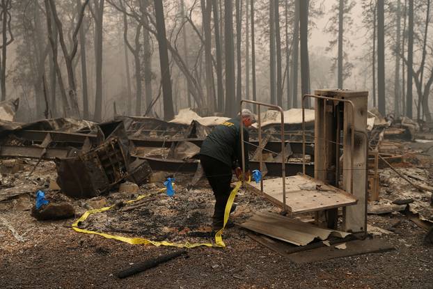 FILE PHOTO: A Butte County Sheriff deputy places yellow tape at the scene where human remains were found during the Camp fire in Paradise