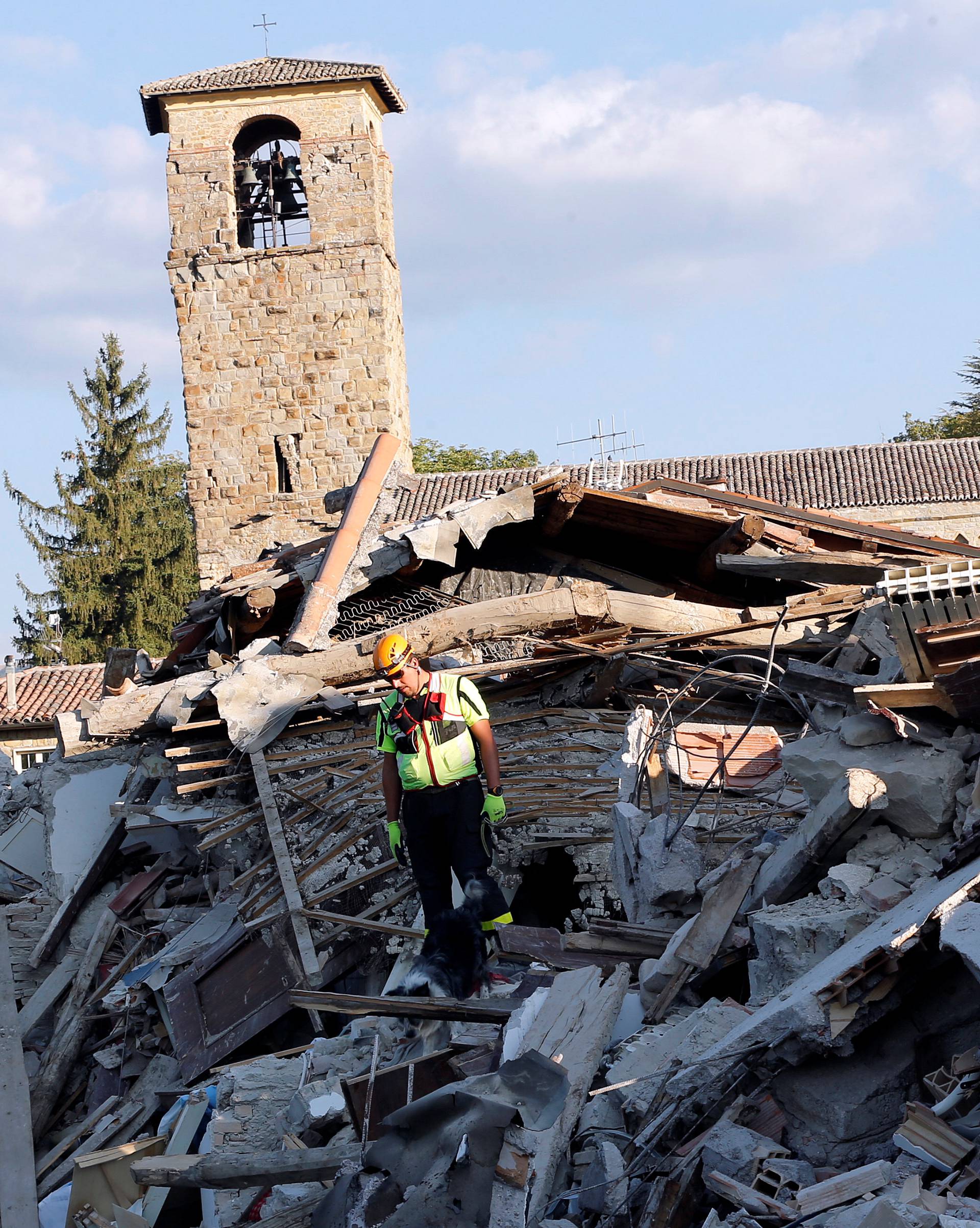 A rescue worker and a dog search among debris following an earthquake in Amatrice
