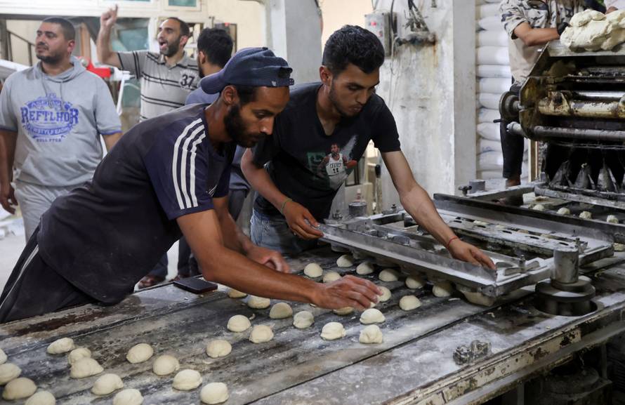 Palestinian workers prepare bread in a bakery that returned to operation after being closed due to a flour shortage, in Deir Al-Balah