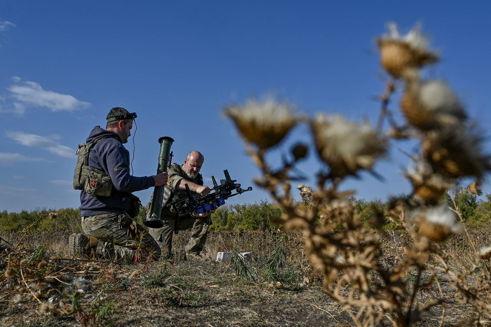 Ukrainian servicemen attach a portable grenade launcher to an FPV drone before a test fly at their position near a frontline in Zaporizhzhia region