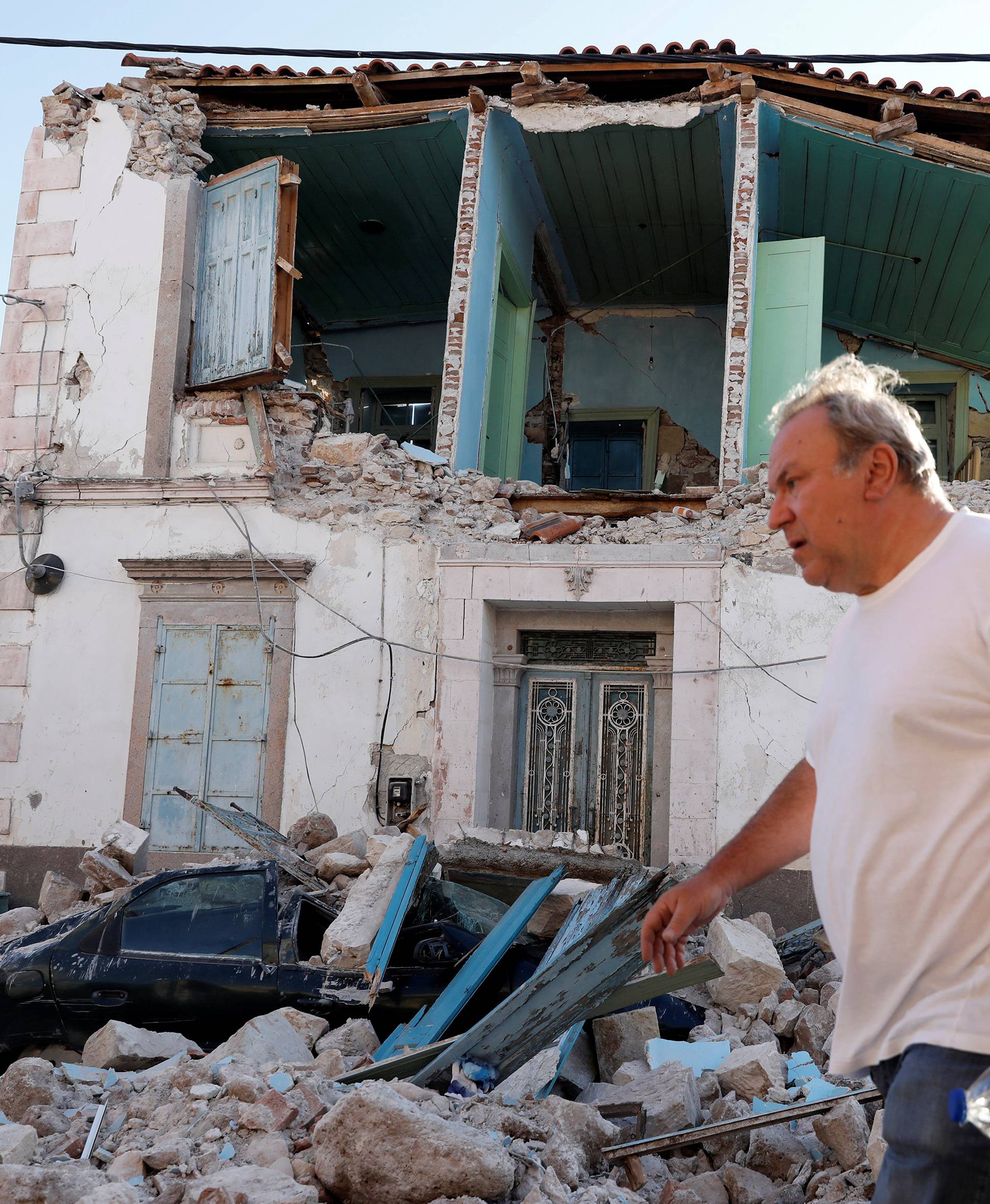 A man walks past a damaged building at the village of Vrissa on the Greek island of Lesbos, Greece, after a strong earthquake shook the eastern Aegean