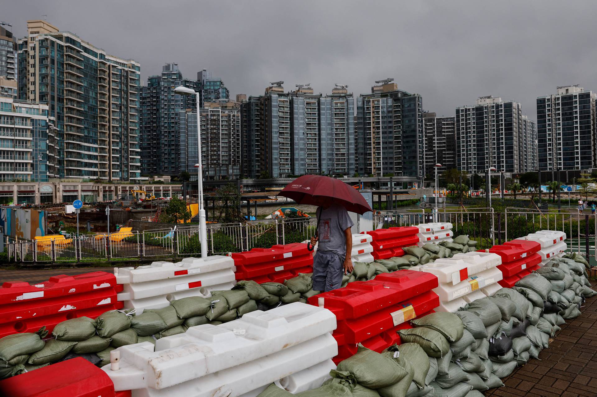 A man holds an umbrella as he walks past sandbags following Super Typhoon Saola in Hong Kong