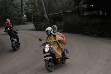 Motorists drive on a road covered in volcanic ash from Mount Agung's eruption in Karangasem