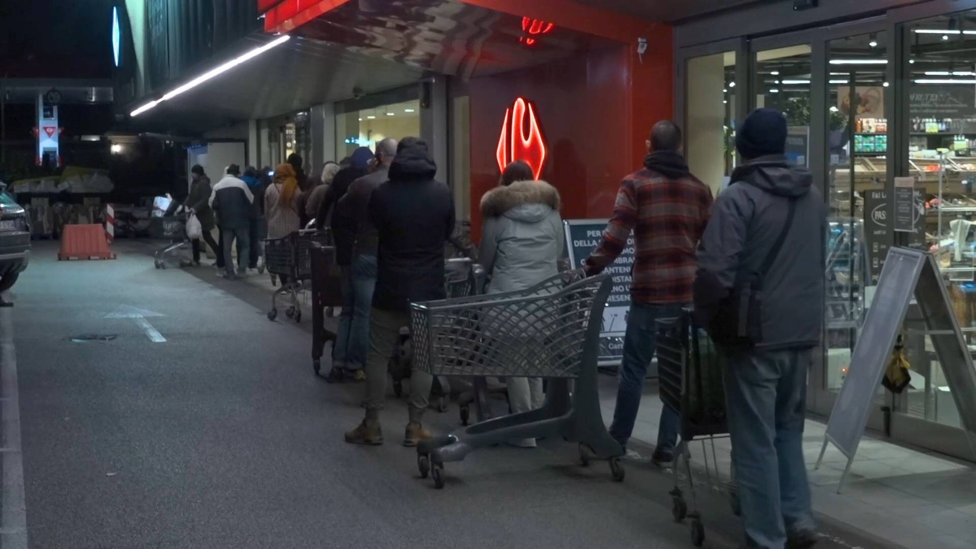 A long queue of people wait with trollies outside a supermarket in the early hours of the morning in Rome