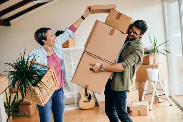 Happy,Couple,Having,Fun,With,Carboard,Boxes,While,Moving,Into