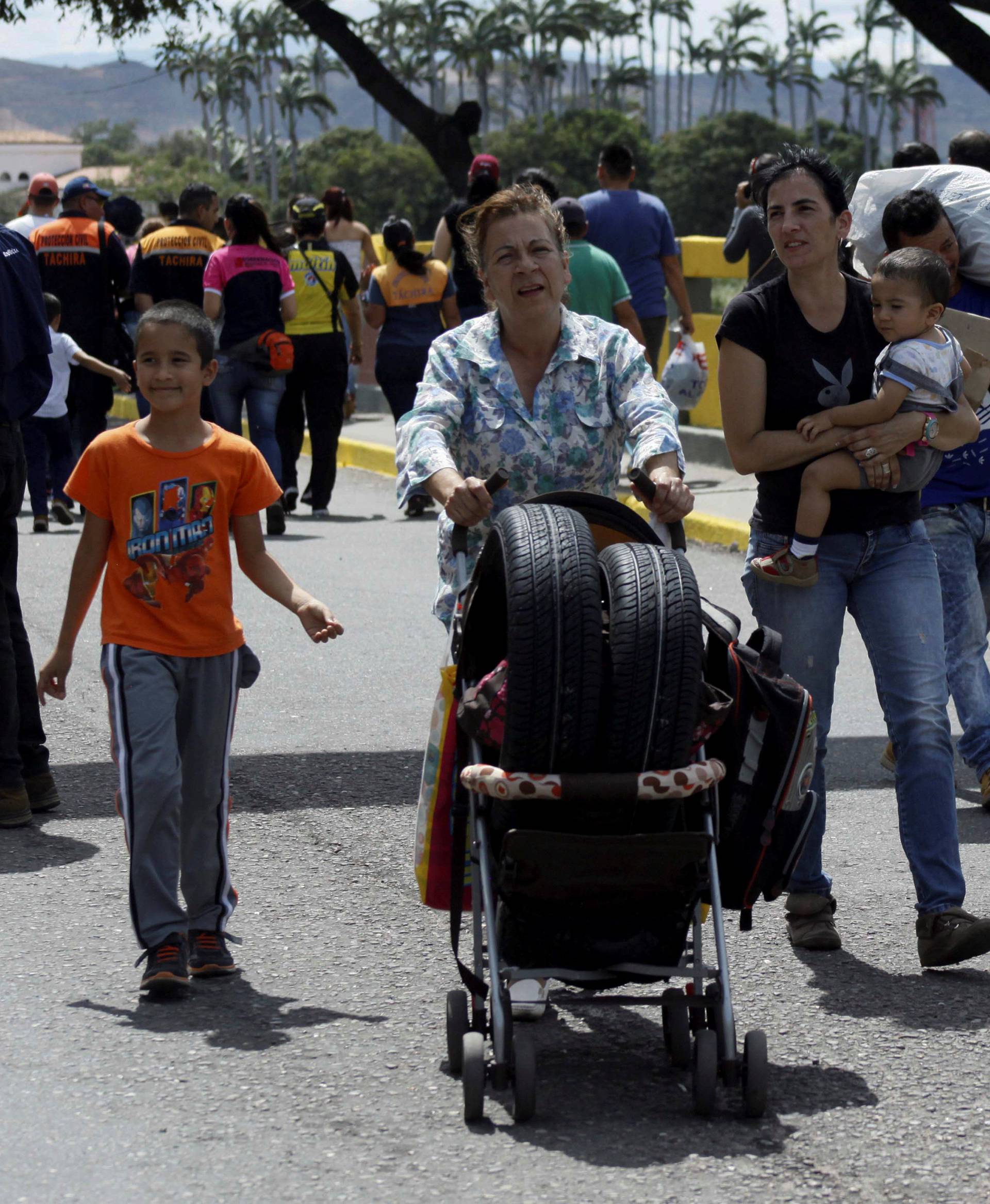 A woman carries tires on a baby stroller while she crosses to Venezuela over the Simon Bolivar international bridge after shopping in Cucuta