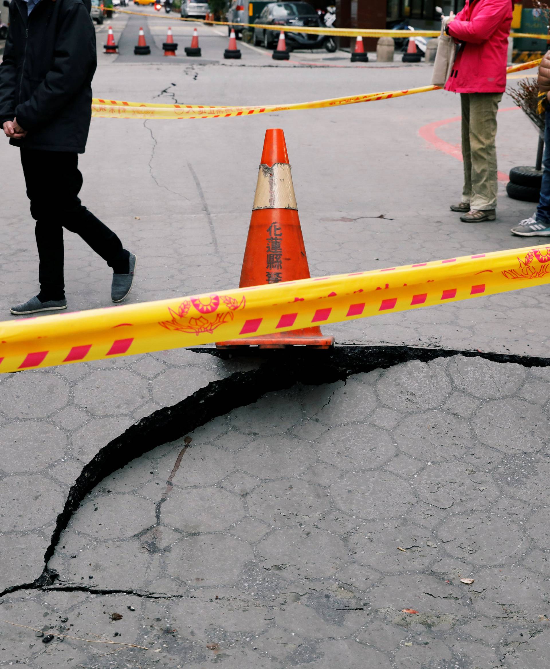 A passerby walks behind cracks on a street after an earthquake hit Hualien