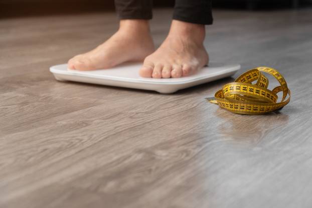 closeup female legs on a measuring scale. Weight loss control concept copy space