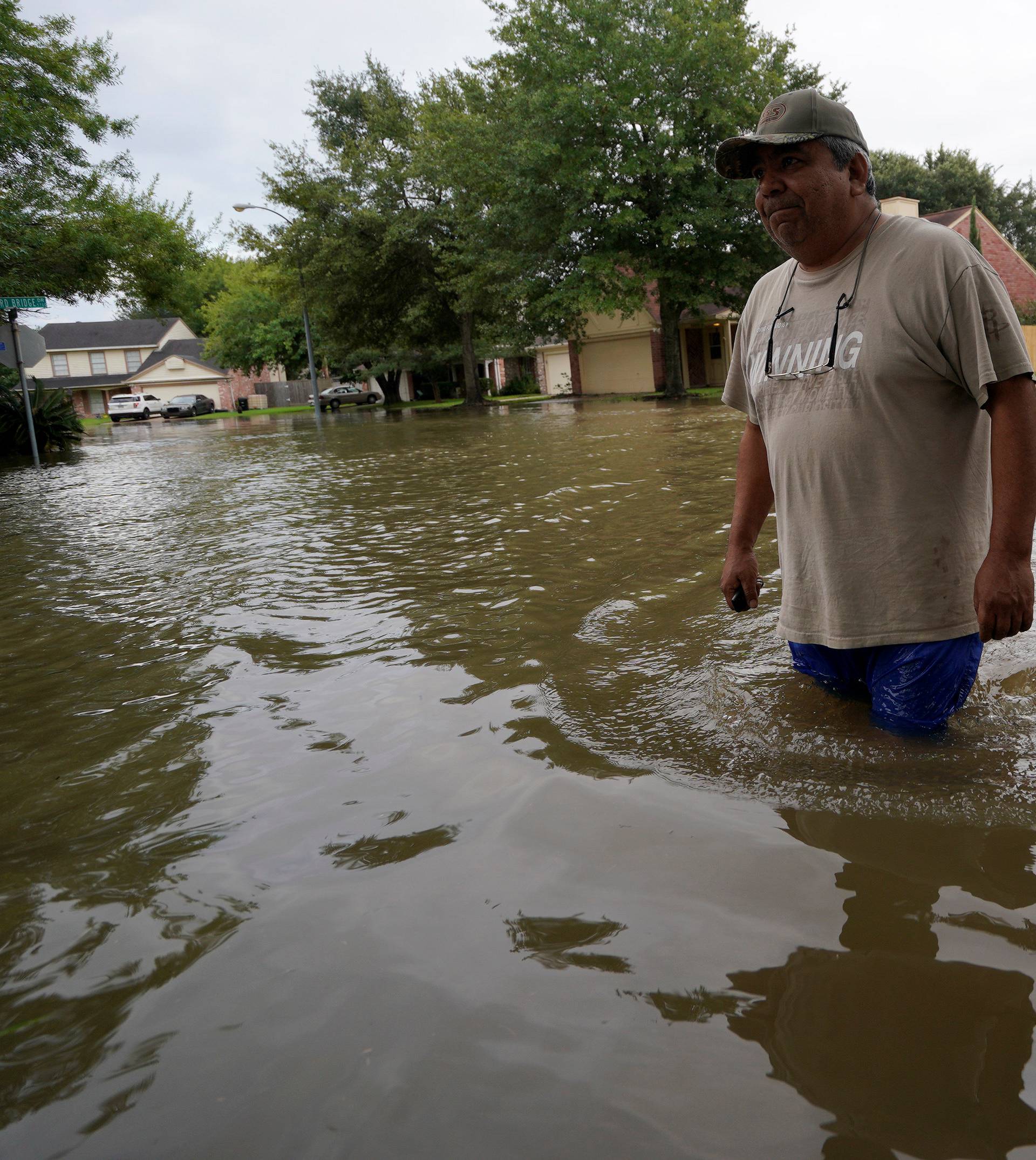 Men walk out of Tropical Storm Harvey floodwaters in north western Houston