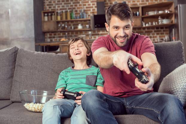 Cheerful,Father,And,Son,Playing,Video,Game,At,Home