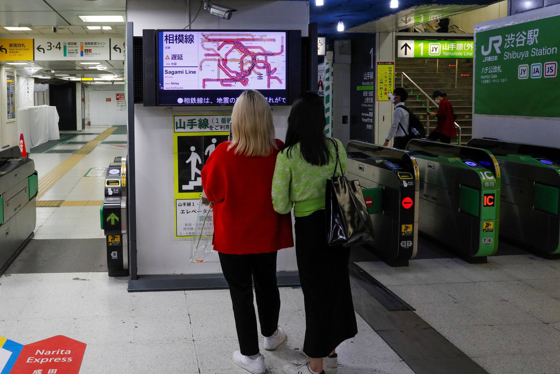 People watch a monitor at Shibuya station, as train services are suspended due to an earthquake, in Tokyo