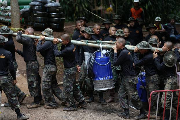 Military personnel carry a water pump machine as they enter the Tham Luang cave complex, where 12 boys and their soccer coach are trapped, in the northern province of Chiang Rai