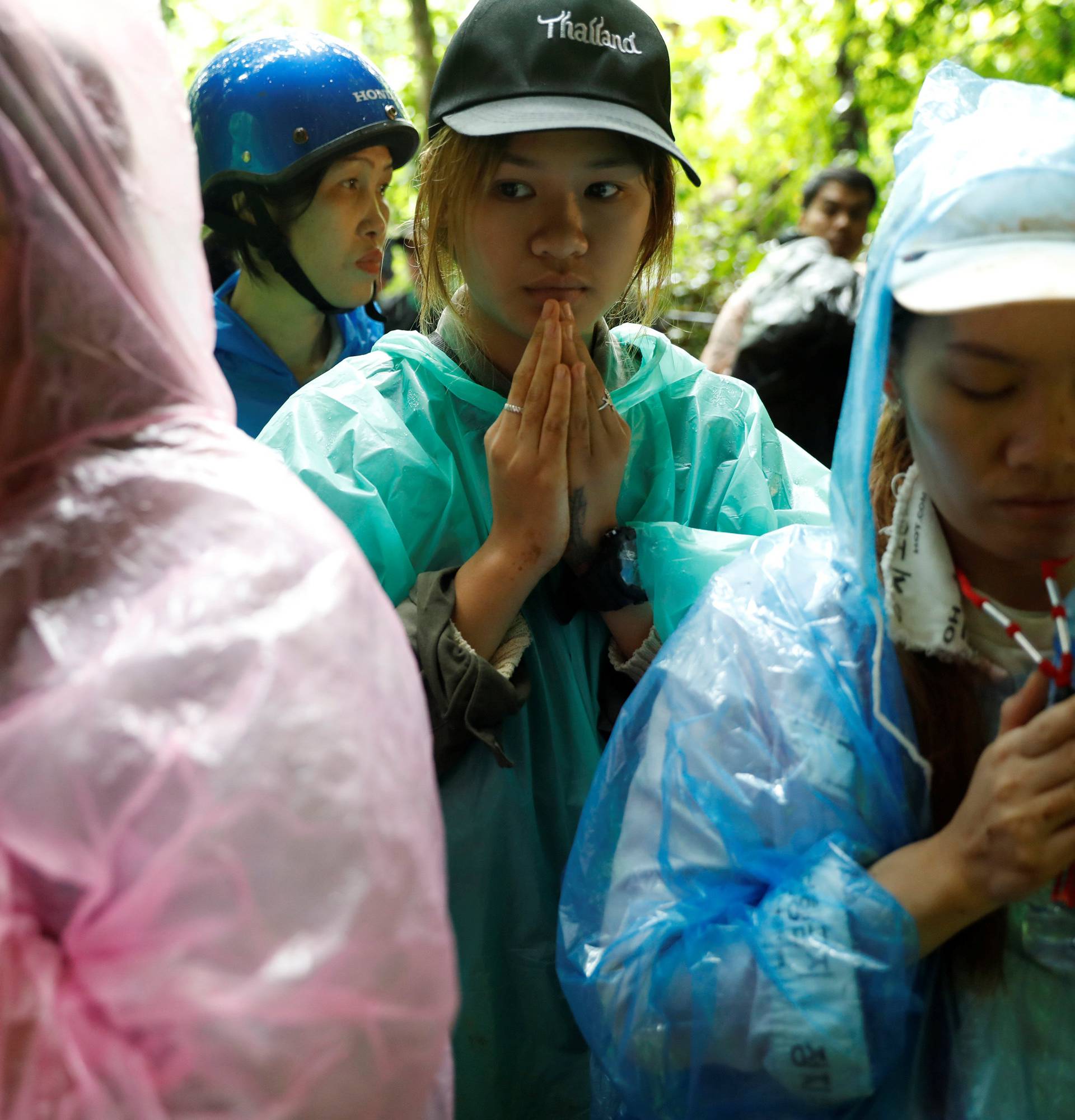 Family members pray near Tham Luang caves during a search for 12 members of an under-16 soccer team and their coach, in the northern province of Chiang Rai
