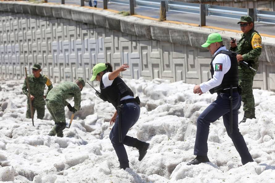 Security forces and soldiers try to clear away ice after a heavy storm of rain and hail which affected some areas of the city in Guadalajara