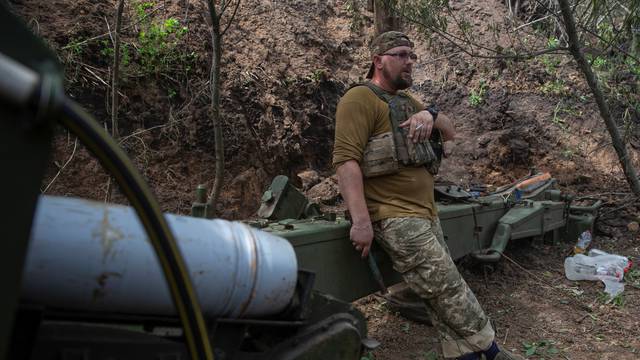 Ukrainian serviceman smokes a cigarette next to a 2A36 Giatsint-B howitzer at a position near a front line in Donetsk region