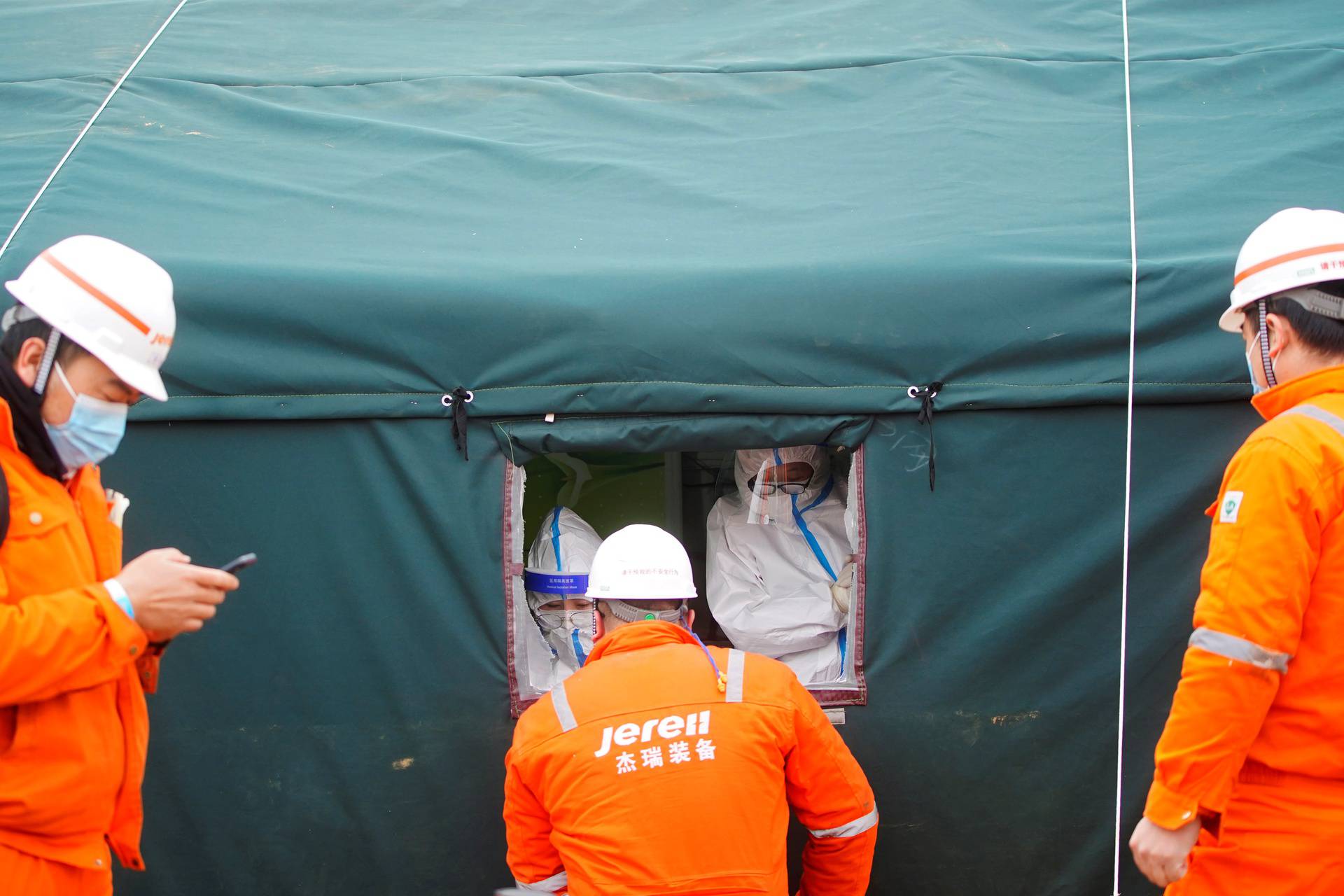 Medical workers in protective suits collect swabs from rescue workers at the Hushan gold mine in Qixia