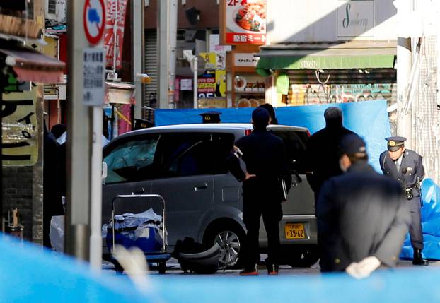 Policemen stand next to a car which plowed into pedestrians on New Year day in Tokyo