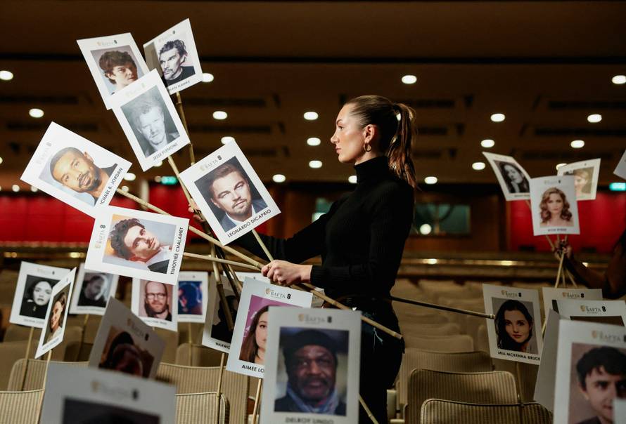 A model poses while holding place sticks for guests during preparations for the BAFTA awards in London