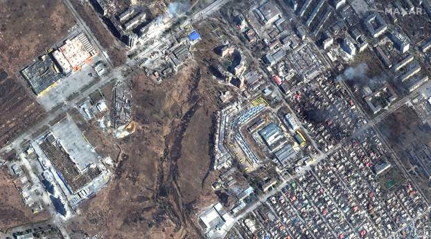 A satellite image shows natural color overview of damage and fires burning, at Prymorskyi district, western Mariupol