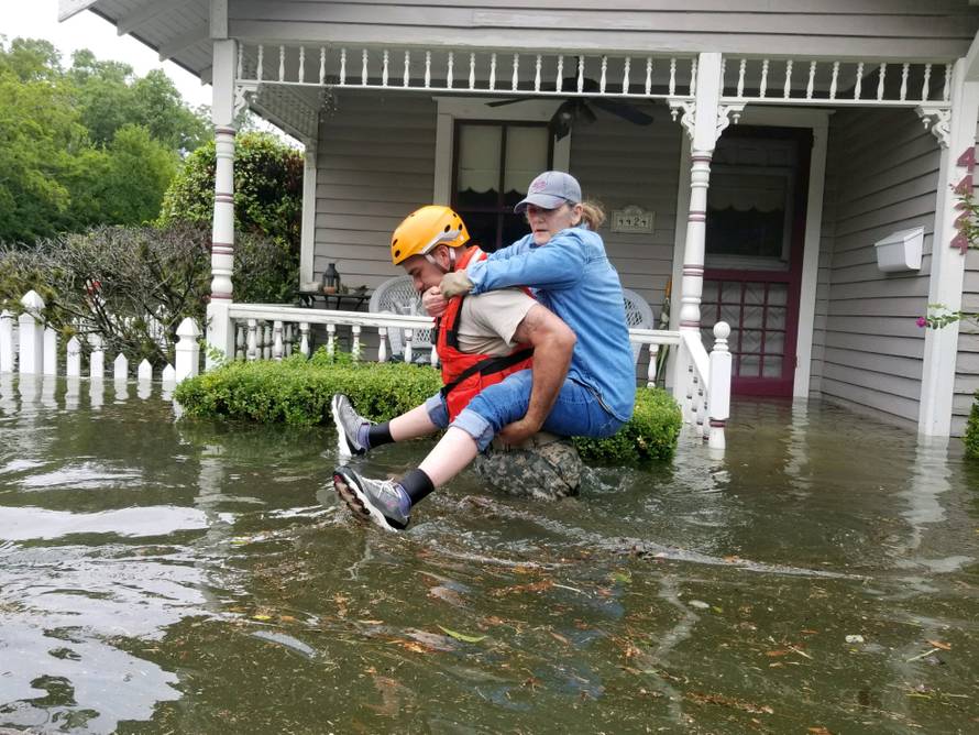 Handout photo of a Texas National Guard soldier carries a woman on his bank as they conduct rescue operations in flooded areas around Houston