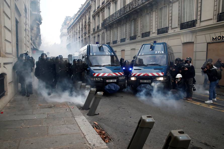 Tear gas floats in the air around French gendarmes who secure a street during a national day of protest by the "yellow vests" movement in Paris