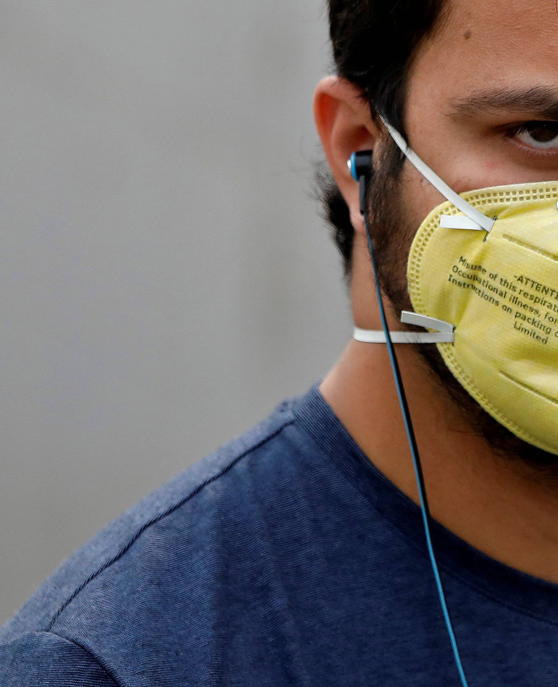 A man wearing a mask walks outside a metro station on a smoggy morning in New Delhi