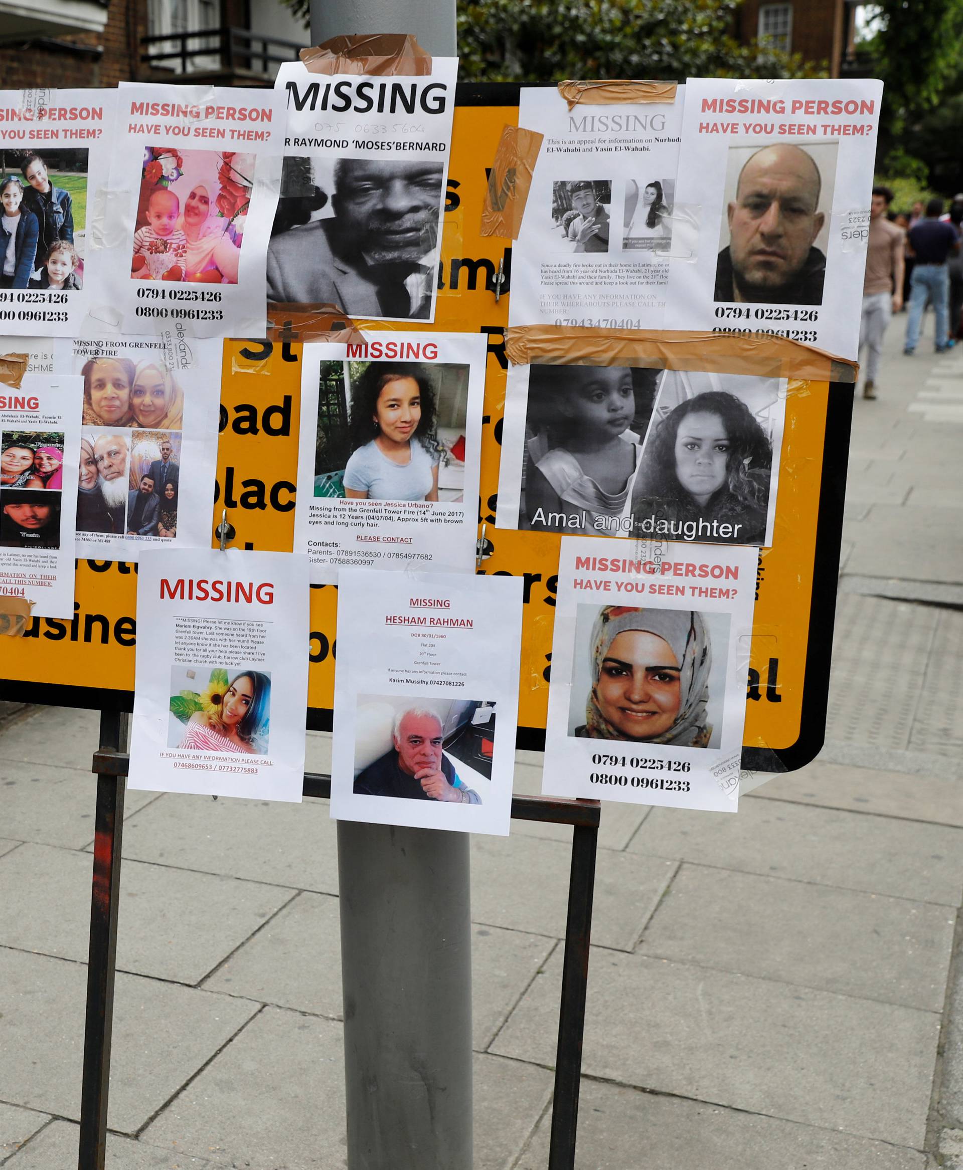 A woman stands by missing person posters near The Grenfell Tower block, destroyed by fire, in north Kensington, West London