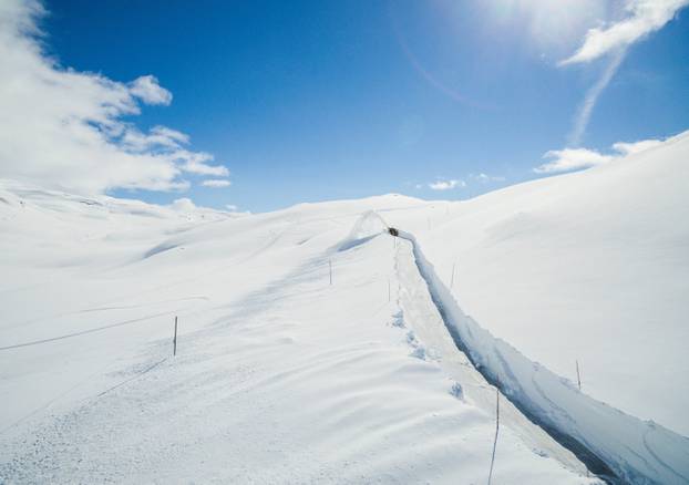 A machine works its way through the snow, clearing the road crossing the mountain Sognefjellet, in Krossbu