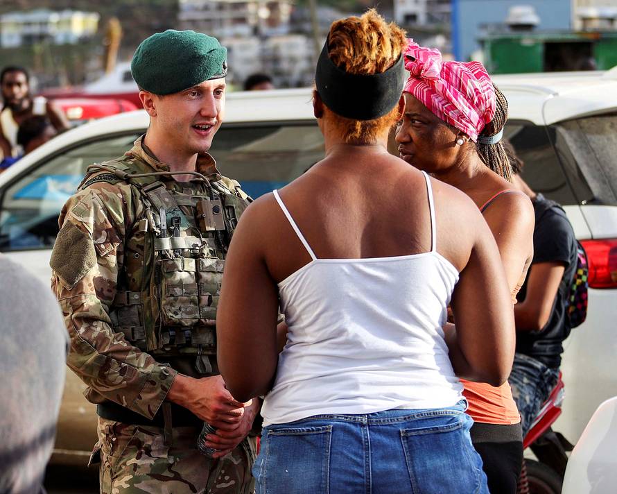 A Royal Marine is seen talking to local residents during a patrol in Tortola, British Virgin Islands