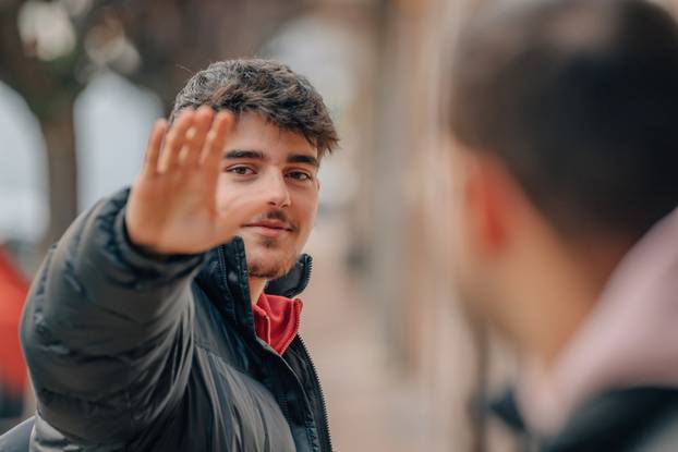 young man in the street waving
