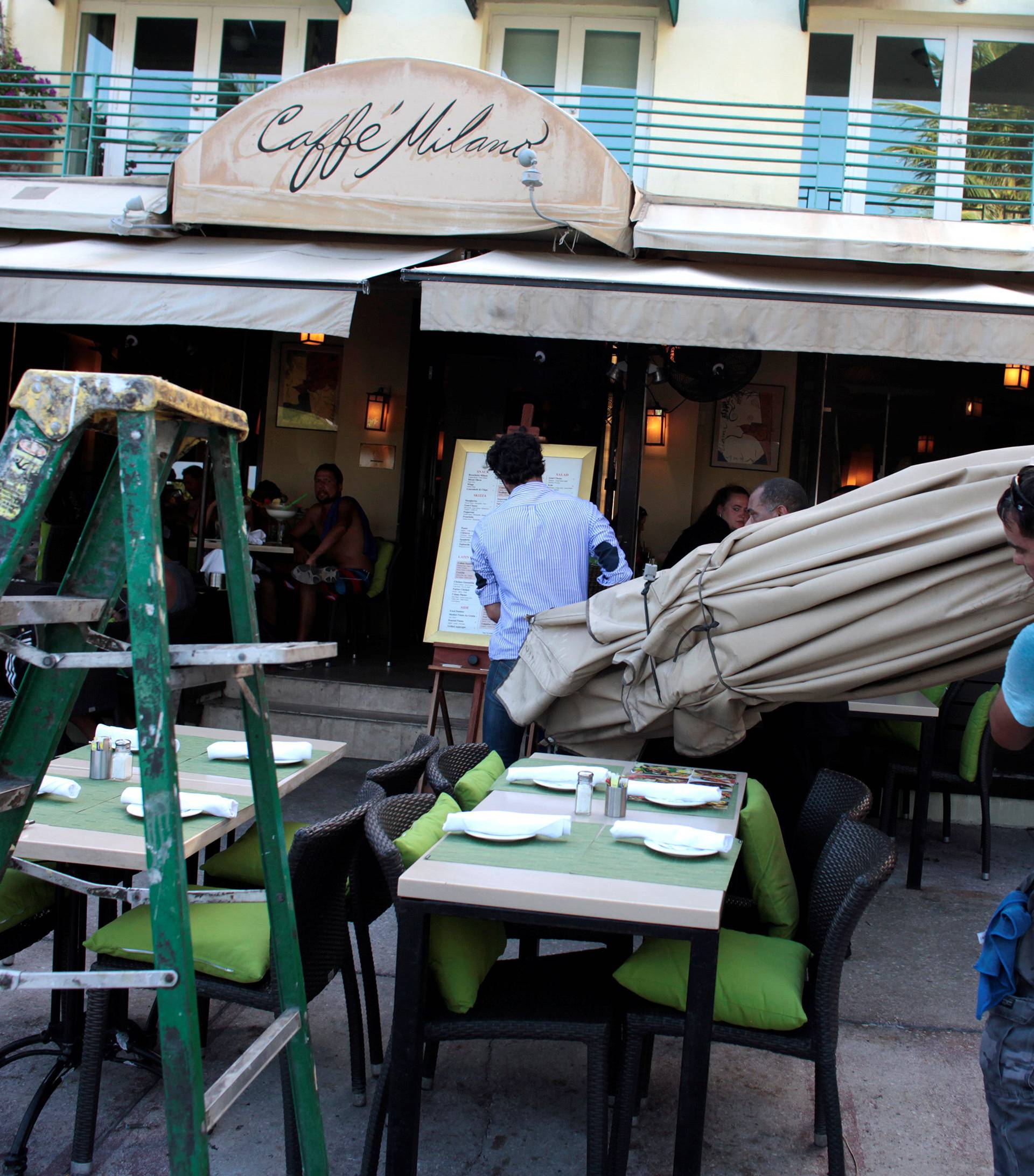 Workers remove umbrellas at Caffe Milano in anticipation of Hurricane Matthew in South Beach