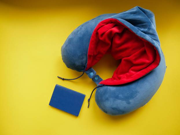 Blue travel pillow isolated on yellow background.