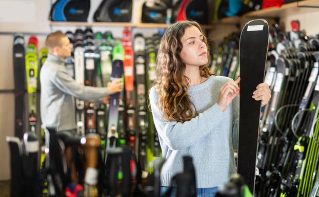 Happy,Woman,Shopper,Choosing,New,Skis,In,Shop,Of,Sports