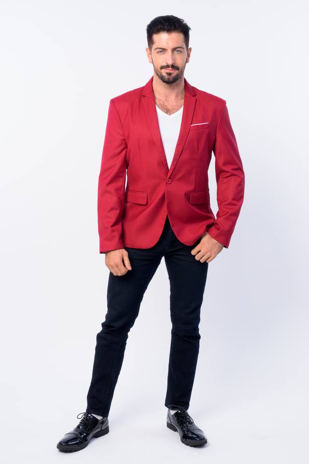 Full body shot of young handsome bearded businessman in red suit