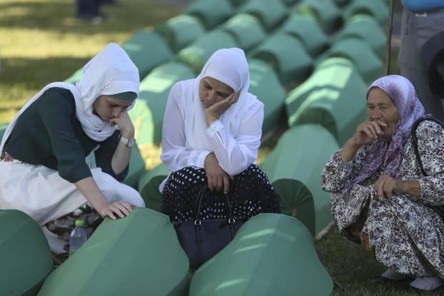Women cry near coffins of their relatives, who are newly identified victims of the 1995 Srebrenica massacre, which are lined up for a joint burial in Potocari near Srebrenica